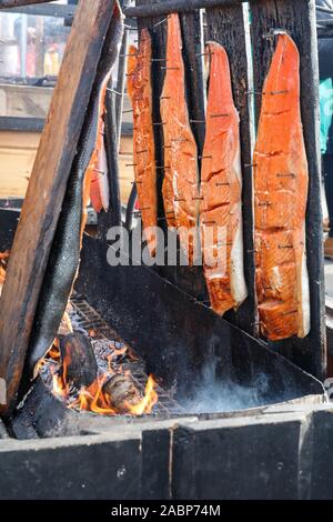 Loimulohi, fiamma o di Salmone Salmone autocollimanti. Filetto di salmone inchiodati ad un consiglio di amministrazione e cotte al calore di un fuoco aperto. Tradizionale cucina finlandese. Foto Stock