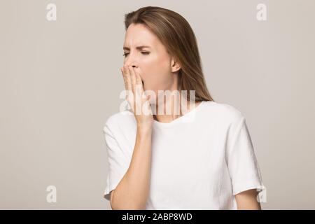 Sonno stanco giovane donna sbadigli, che copre la bocca con la mano Foto Stock