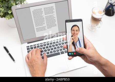 Medico con uno stetoscopio sullo schermo dello smartphone. La telemedicina o la telesanità concetto. Foto Stock