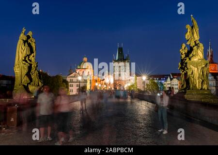 Karluv, la maggior parte delle persone sul Ponte Carlo al tramonto, nel retro cupola della chiesa Kreuzherrenkirche con torre del ponte della città vecchia di Praga, Boemia Foto Stock