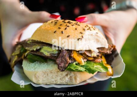 Panino con carne di agnello, spinaci e formaggio fuso ad una street market alimentare. Foto Stock