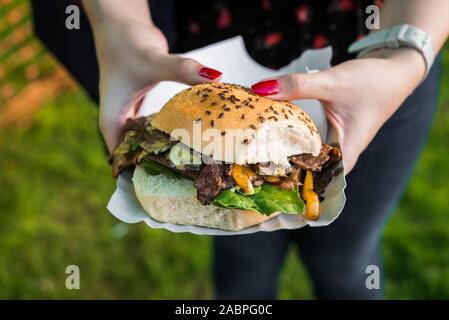 Panino con carne di agnello, spinaci e formaggio fuso ad una street market alimentare. Foto Stock