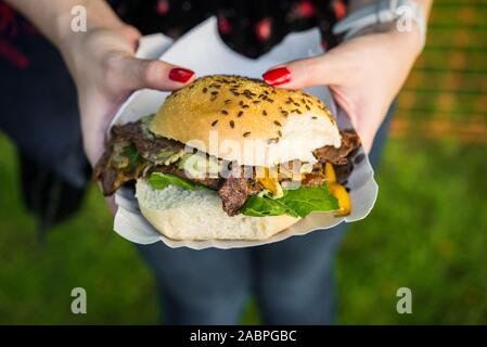 Panino con carne di agnello, spinaci e formaggio fuso ad una street market alimentare. Foto Stock