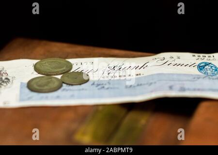 Alcune vecchie monete Britanniche sedersi sulla parte superiore di un assegno bancario da 1940 durante la seconda guerra mondiale 2 Foto Stock