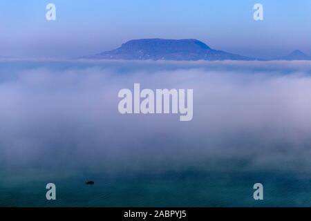 Vista di foggy Balaton from Fonyód promenade con il Badacsony in background su una giornata autunnale. Foto Stock