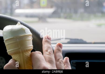 Uomo con gelato al volante di una vettura Foto Stock