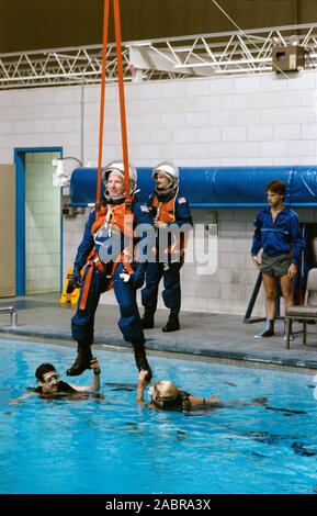 S90-34964 (16 aprile 1990) --- astronauta Vance D. Marca, STS-35 commander è sospeso tramite il suo paracadute cablaggio sopra la piscina nel centro spaziale Johnson?s (JSC) Ambiente eterea Training Facility (WETF) Bldg 29 durante il lancio di emergenza esercizi egress. I subacquei in piscina in attesa del marchio piedi costante per lui. In background e sul lato della piscina è Guy pilota S. Gardner. Entrambi i brand e Gardner indossa il lancio e tute di entrata (LES) e lanciare e caschi di entrata (LEH). Foto Stock