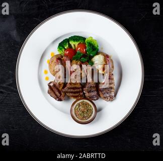 Costolette di carne in salsa con patate al forno e broccoli Foto Stock
