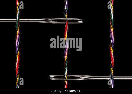 Due grandi occhi Aghi da cucire su un campo nero con 3 Twisted multi-thread di colore. Camera per copiare in vari luoghi. Forte mette in luce con gli aghi Foto Stock