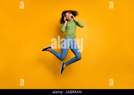 Lunghezza piena dimensione corpo foto di casual allegro positivo piuttosto carina ragazza in jeans denim jumping ascoltando musica isolato colori vividi Foto Stock