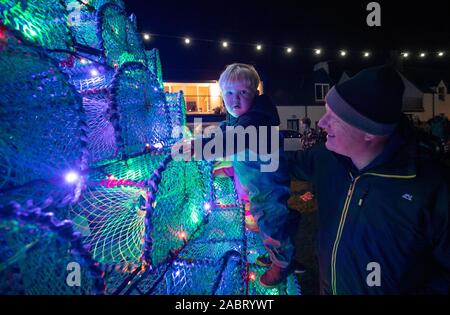 Aly Loening, di età compresa tra i 2, da Dunbar, East Lothian, con il suo nonno Topher Dawson, richiede uno sguardo più da vicino al 16ft albero di Natale sul porto-lato in Ullapool, Wester Ross, che viene creato da 340 pesca cantre utilizzati per la cattura di gamberetti e di granchi. Foto Stock