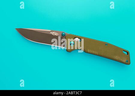 Chiusura-coltello su un sfondo turchese. Pocketknife militare di colore. Un singolo oggetto. Ribaltarsi metallico. Foto Stock