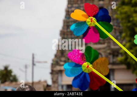 Colorate il mulino a vento di plastica sul bastone giallo contro il tempio indiano sfondi Foto Stock