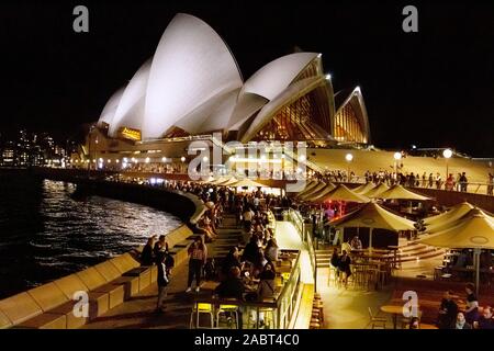 Sydney Opera House e sydney Harbour di notte - bar affollati da gente che si gode la vita notturna; Sydney Australia Foto Stock