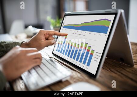 Close-up di un imprenditore il canto analizzando il grafico su computer portatile al lavoro Foto Stock