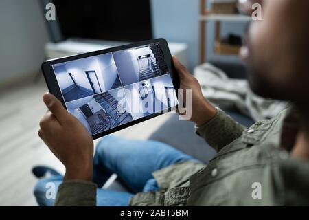 Persona le telecamere di monitoraggio Live View di casa sulla tavoletta digitale Foto Stock