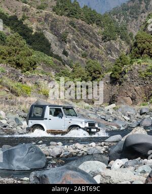 La trazione a quattro ruote motrici guidando attraverso il flusso nel canyon Barranco de las Angustias, Valle di paura, de la Caldera de Taburiente, La Palma Isole Canarie Spagna Foto Stock