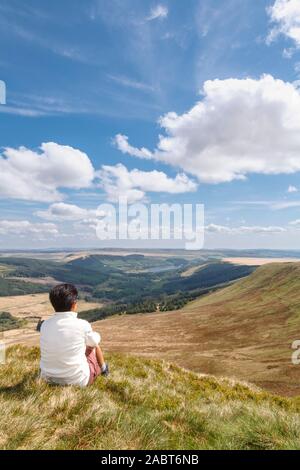 Indian (British asiatica) donna seduta su una collina guardando la vista. Pen Y ventola, Brecon Beacons, Wales, Regno Unito Foto Stock