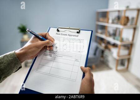 Close-up di mano di una persona il riempimento di valutazione immobiliare forma con penna Foto Stock