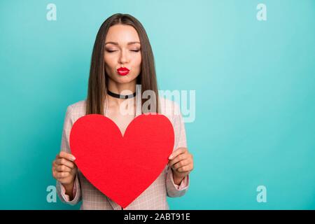 Close-up verticale di Nizza attraente amabile dolce gara straight-ragazza dai capelli tenendo in mano un grande cuore invio kiss isolato sul luminoso brillare vividi Foto Stock