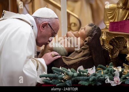 Papa Francesco bacia un bambino Gesù figura (statua) come egli arriva a celebrare l'Epifania la Santa Messa nella Basilica di San Pietro e la Città del Vaticano. Foto Stock