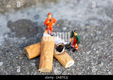 Due minuscoli immondizia puliscono e spazzano le sigarette fumate sulla strada che inquinano l'ambiente Foto Stock