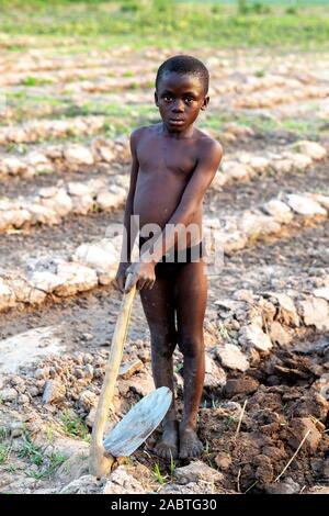 Ragazzo di scavare un campo in Karsome, Togo. Foto Stock