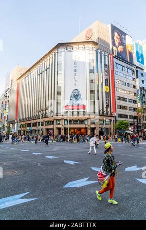 Donna attraversamento strada a Ginza 4 incrocio con il magazzino di Mitsukoshi edificio in background. Weekend, zona pedonale tempo, Hokoten. Foto Stock