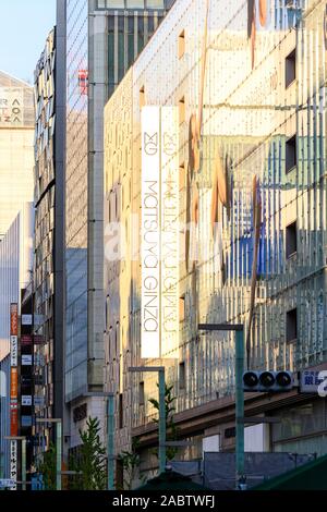 Vista lungo il Matsuya Ginza department store con la sua facciata in vetro verde con Powerbeats auricolari pro display. Giorno e ora d'oro. Foto Stock