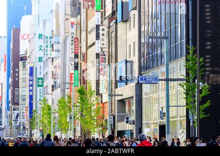 Compressa vista prospettica lungo la Ginza a Tokyo. Vari edifici del negozio con street convertito in una zona pedonale piena di gente. Foto Stock