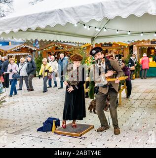 One-man band e accompagnamento vocalist femminile e cucchiai player divertente la folla all'aperto al pubblico e con ingresso gratuito 2019 Mercatino di Natale a Chatsworth House Foto Stock