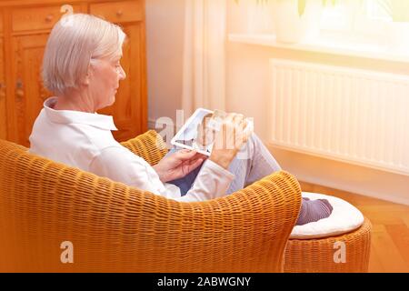 E-id concetto: senior donna usando un video servizio di identificazione per aprire un nuovo conto corrente bancario con il suo tablet pc Foto Stock