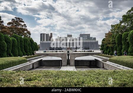 I turisti passeggiano in Hiroshima Parco del Memoriale della Pace di Hiroshima, Giappone con l'Hiroshima Peace Memorial Museum in background. Foto Stock