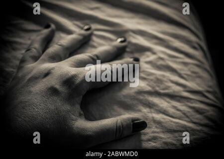 Un close-up di una donna di mano sul letto in bianco e nero Foto Stock