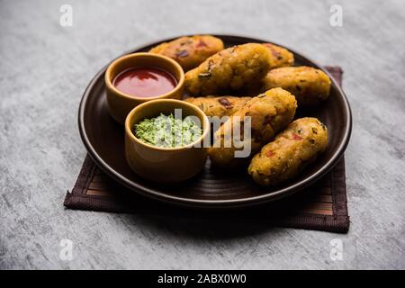 Frittatine di riso flated o POHA di verdure servite con ketchup di pomodoro e chutney verde Foto Stock