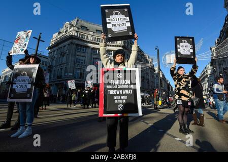 Londra, Regno Unito. Il 29 novembre 2019. Membri della ribellione di estinzione inscenare una protesta a Oxford Circus sul Venerdì nero. Gli attivisti protestano contro usa e getta di moda e di un eccessivo consumo dei consumatori il giorno quando i rivenditori stanno offrendo notevoli sconti sui loro prodotti. Credito: Stephen Chung / Alamy Live News Foto Stock