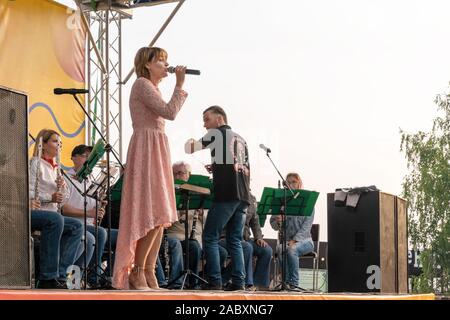 Krasnoyarsk, Russia, Agosto 25, 2019: femmina cantante solista in un abito rosa canta all'aperto, sulla strada per l'accompagnamento del reggiseno di Krasnoyarsk Foto Stock