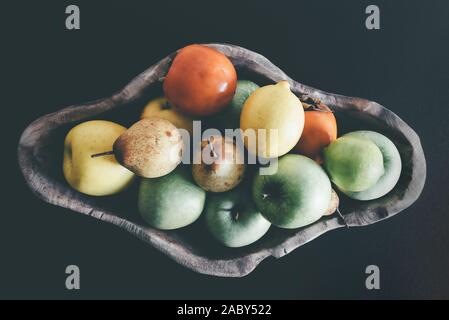 Vista superiore della frutta organica nella ciotola di legno scuro su sfondo tabella Foto Stock