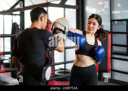 Giovane donna asiatica boxer colpisce con un gomito al trainer professionale nella boxe studuim in background in palestra per il fitness. Montare sportivo per una sana vita Foto Stock