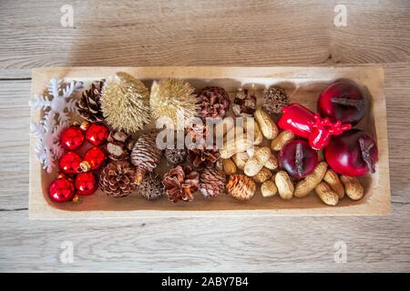 Decorazione di Natale per la casa. Con luci e palline corona di Avvento e un angelo. Decorata splendidamente in ciotole di legno. Foto Stock