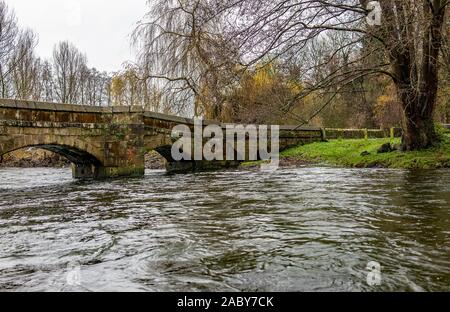 Vista da una prospettiva bassa del ponte di pietra sul fiume Wye, in piena alluvione scoppia e le sue banche, nel Derbyshire città di Bakewell Foto Stock