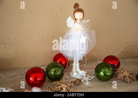 Decorazione di Natale per la casa. Con luci e palline corona di Avvento e un angelo. Decorata splendidamente in ciotole di legno. Foto Stock