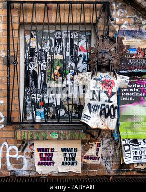 Muro di mattoni del viadotto ferroviario con vecchi manifesti, adesivi, graffiti e metallo riciclato scultura in Mitte-Berlin, Germania Foto Stock