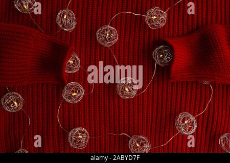 Sferica luci metallico sulla maglia maglione rosso. Natale e Anno Nuovo umore Foto Stock
