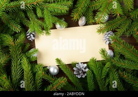 Piatto mockup laici di vacanza greeting card fatta di marrone carta craft Abete rami coni gingerbread cookie e baubles con copy-spazio Foto Stock