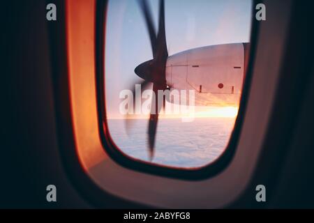 Vista da finestra di elica aereo durante il volo sopra le nuvole al bellissimo sunrice. Messa a fuoco selettiva sul motore a turboelica. Foto Stock