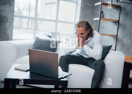 Guardando al momento del guasto. Foto del giovane imprenditore seduto sul pullman e ha sottolineato durante il lavoro Foto Stock