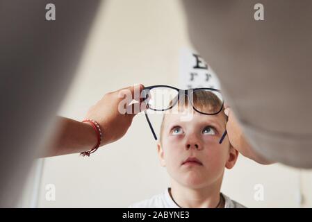 Medico dare al bambino nuovi occhiali neri per la sua visione Foto Stock