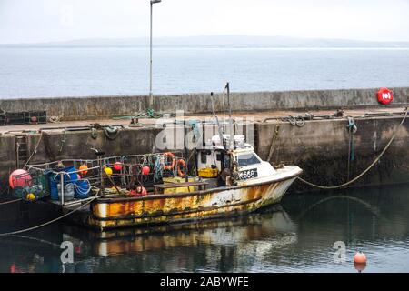 Vecchia barca da pesca ormeggiate nel porto di John O'Semole, con l'isola Orcadian di stroma visibile attraverso il Pentland Firth Foto Stock