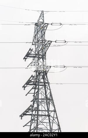 Sistema di distribuzione di elettricità. Alta tensione linea elettrica aerea, potenza del pilone in acciaio, torre tralicciata in piedi in campo. Cielo blu come sfondo. Foto Stock